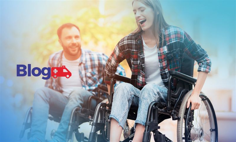 Banner com mulher em primeiro plano e homem em segundo plano, ambos em cadeira de rodas sorridentes andando em local aberto